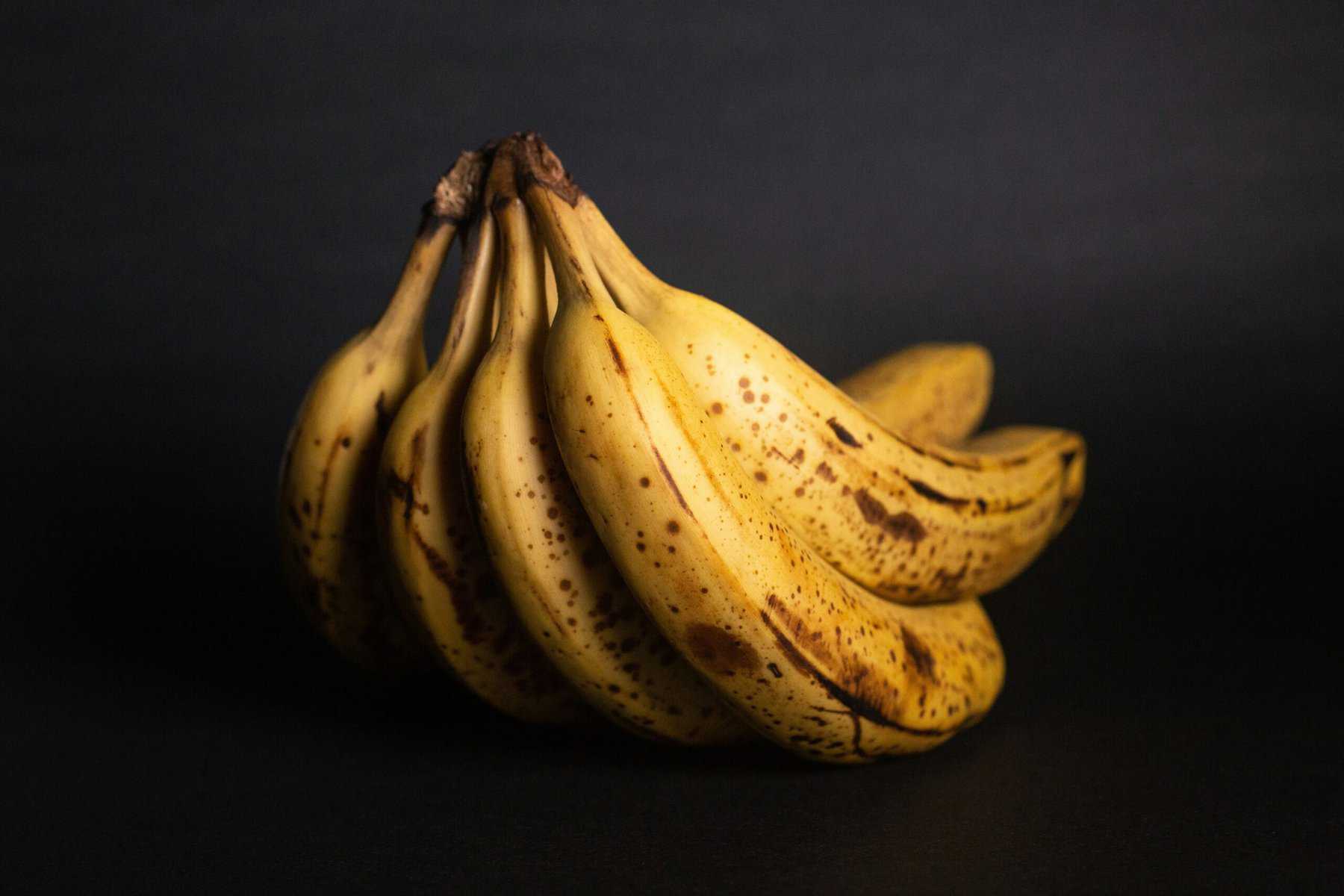 bunch of bruised bananas on black background